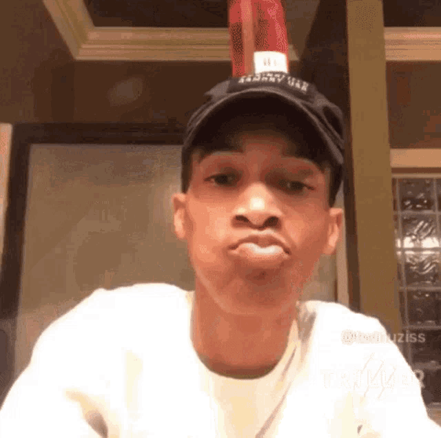 a young man wearing a hat with a bottle of ketchup on top of his head