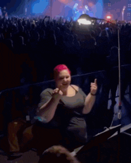 a woman in a pink hat stands in front of a crowd of people