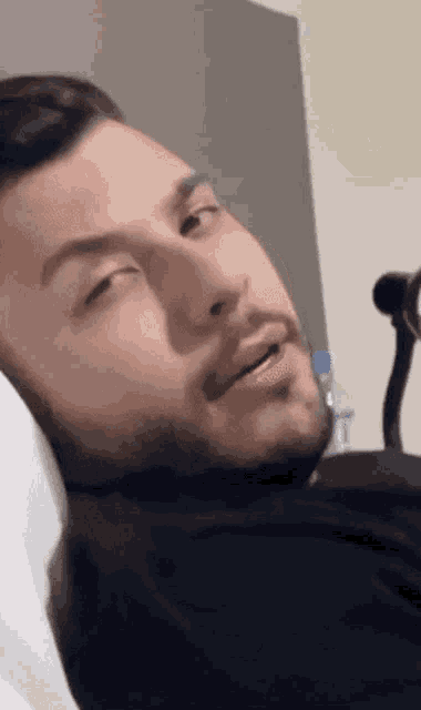 a man with a beard is laying in a hospital bed with his eyes closed