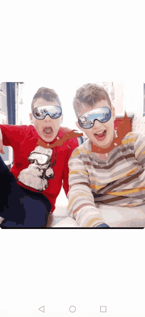 two young boys wearing ski goggles are posing for a photo