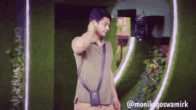 a man in a green shirt is talking on a cell phone in front of a sign that says @monikagoswamiirk