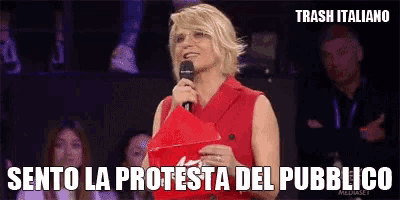 a woman in a red dress is holding a microphone and says trash italiano sento la protesta del pubblico
