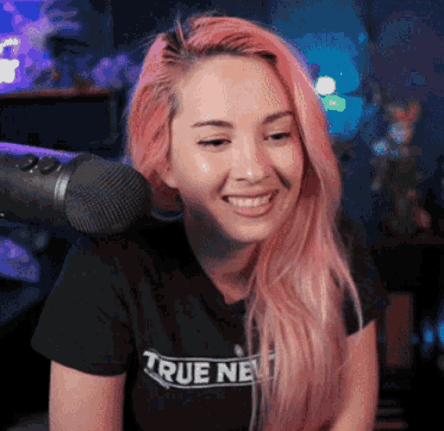 a woman with pink hair wearing a black shirt that says true next