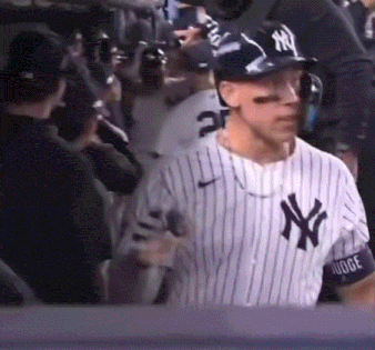 a man in a new york yankees jersey is standing in the dugout .