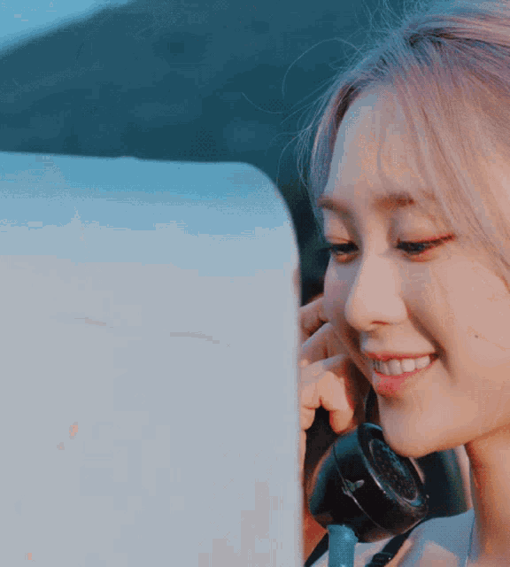 a woman with pink hair is smiling while talking on a telephone