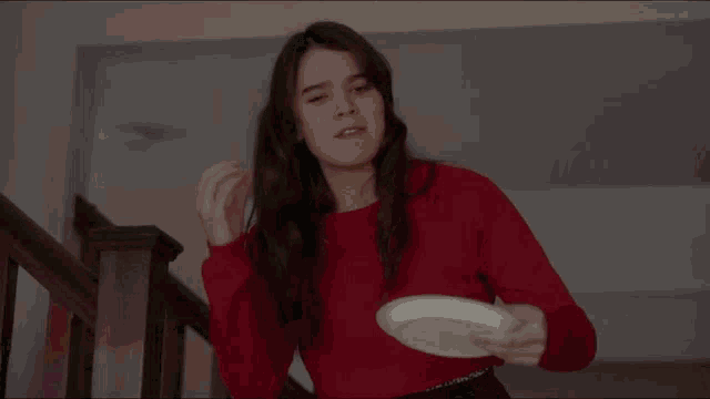 a woman in a red sweater is holding a plate