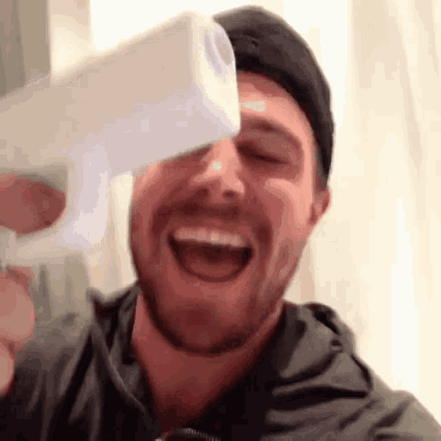a man with a beard is laughing while holding a roll of toilet paper .