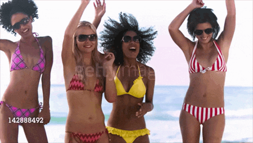a group of women in bikinis are dancing on the beach with the number 142888492 in the corner