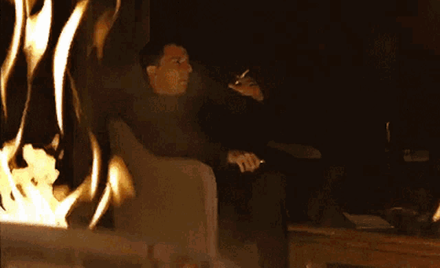 a man smoking a cigarette in front of a fireplace