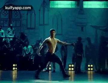 a man without a shirt is dancing on a stage .