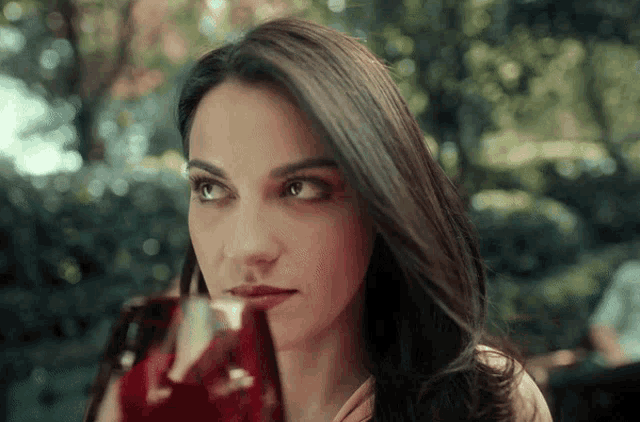 a woman is holding a glass of red liquid in her hand