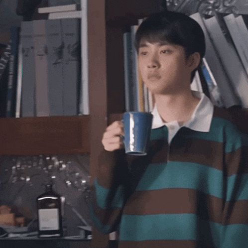 a young man is drinking from a blue cup with a sticker on it that says ' a ' on it