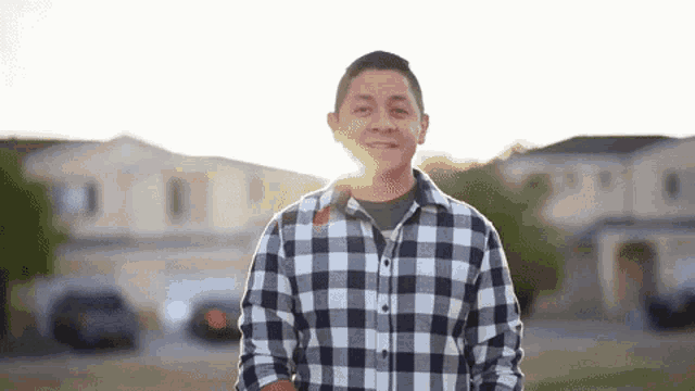 a man in a plaid shirt is standing in front of a row of houses