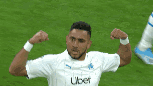 a soccer player wearing an uber jersey flexes his muscles