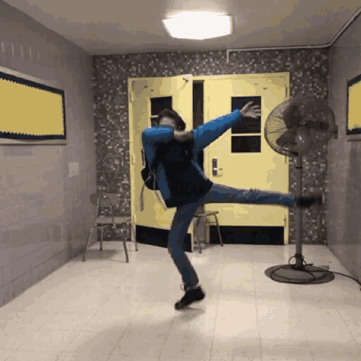 a man in a blue jacket is doing a dab in front of a fan