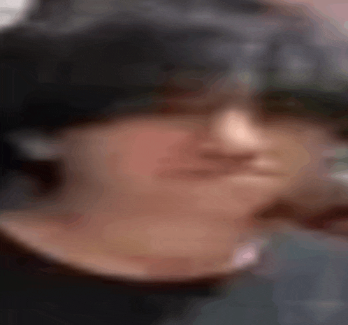 a close up of a person 's face with a blurry background and a hat on .