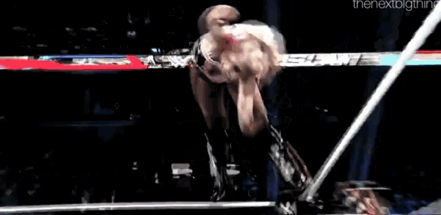 a woman is flying through the air in a wrestling ring while doing a flip .
