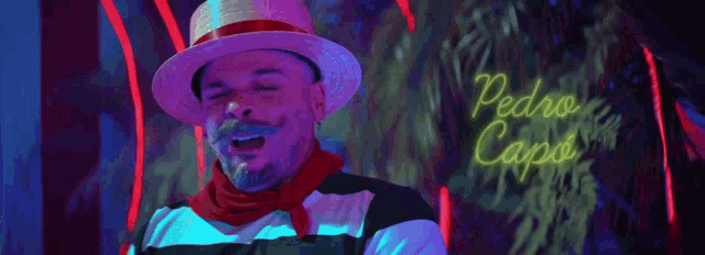 a man wearing a straw hat and a red scarf is standing in front of a neon sign that reads pedro capo