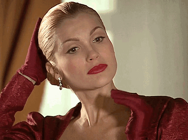 a woman in a red dress and red gloves holds her hand to her face