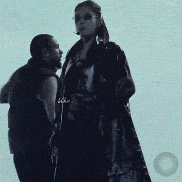 a man and a woman are standing next to each other and the woman has sunglasses on