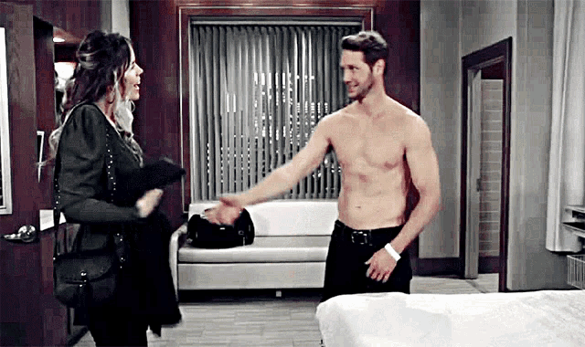 a man without a shirt is standing next to a woman in a room .