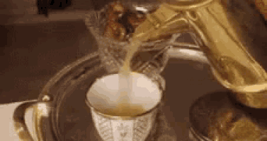 a person is pouring a cup of tea from a teapot .