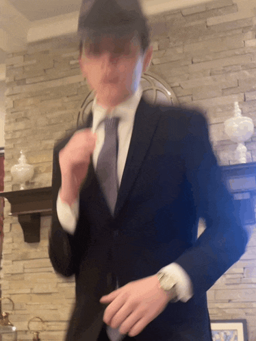 a man in a suit and tie is standing in front of a fireplace