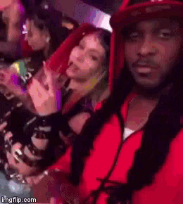 a man in a red hoodie is standing next to a woman in a red dress .