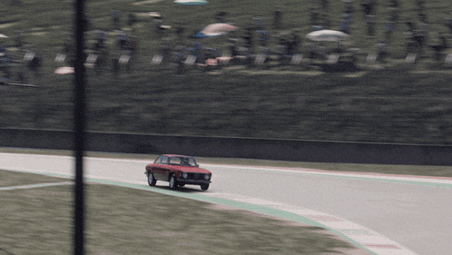a red car is driving on a track with a green stripe on the side