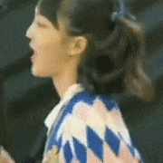 a close up of a woman 's face with a ponytail and a sweater on .