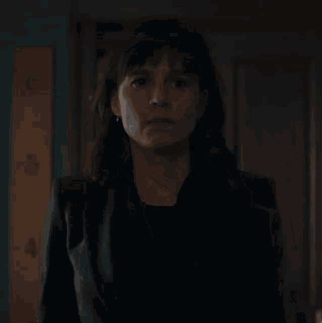 a woman in a suit and black shirt is looking at the camera .