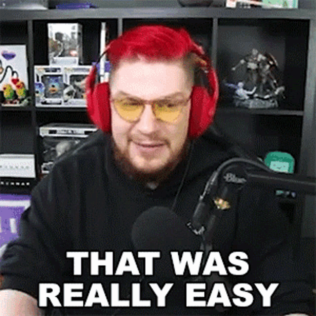 a man with red hair is wearing headphones and glasses and says that was really easy in front of a microphone .