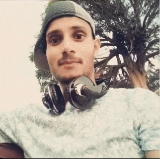 a man wearing headphones and a baseball cap is taking a selfie .