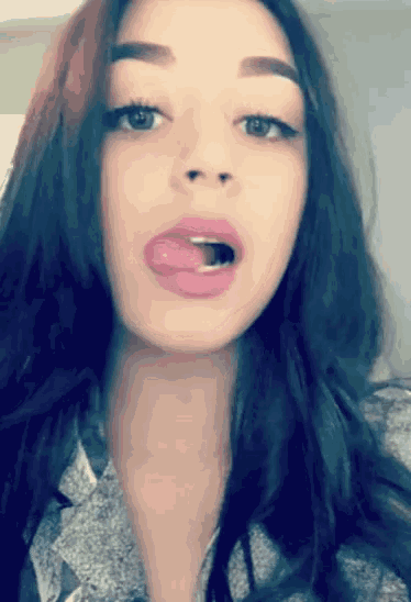 a woman sticking her tongue out while wearing a gray shirt