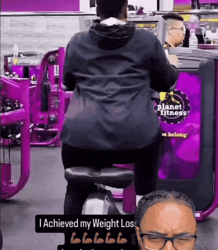 a man is riding an exercise bike in front of a planet fitness sign