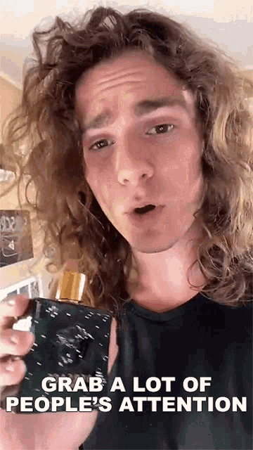 a man with long curly hair is holding a bottle of cologne and says grab a lot of people 's attention