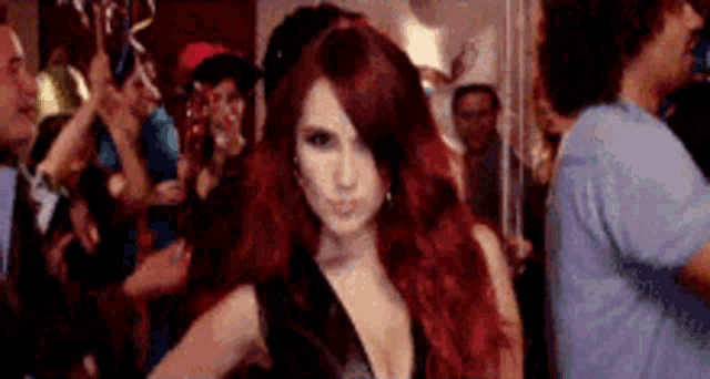 a woman with red hair is standing in front of a crowd at a party .