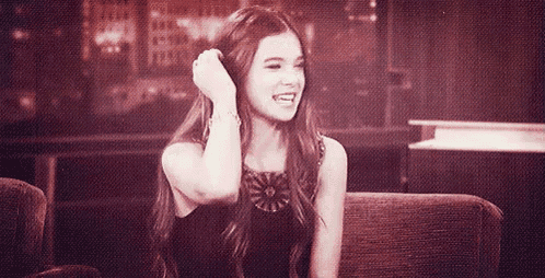a woman with long hair is sitting on a couch and smiling .