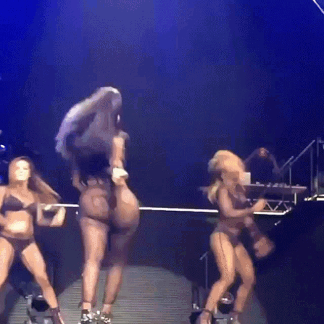 a group of women are dancing on a stage in front of a dj