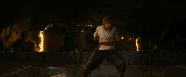 a man is standing in front of a wall with flames coming out of his hands