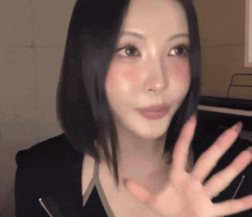 a woman with red cheeks is waving her hand