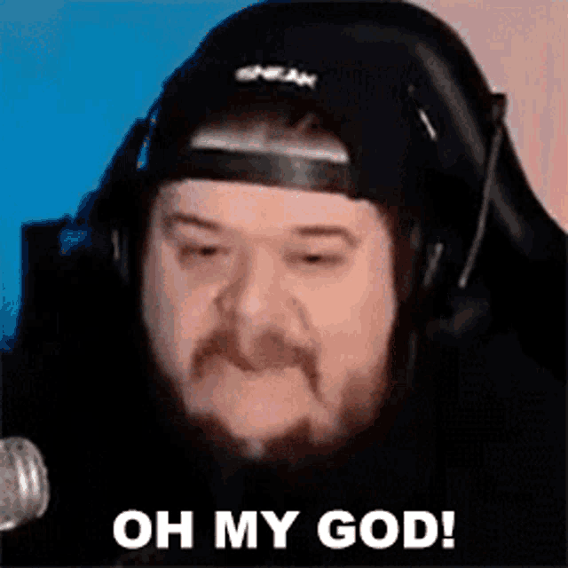 a man with a beard is wearing headphones and a hat and saying `` oh my god '' .