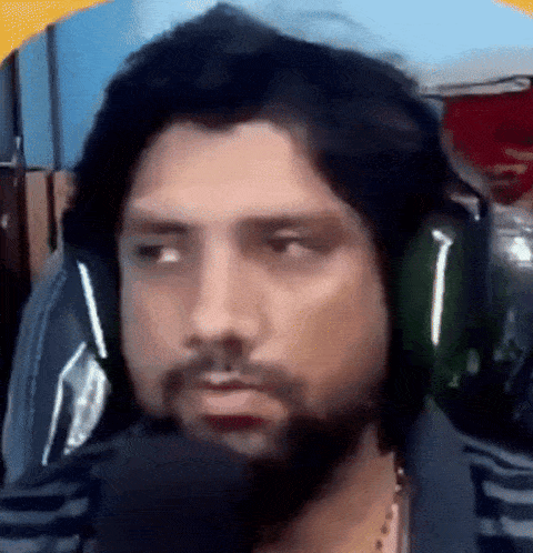 a man with a beard is wearing headphones while sitting in front of a microphone .