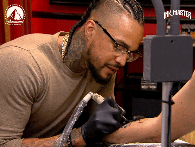 a man is getting a tattoo on someone 's arm with a paramount network logo in the background