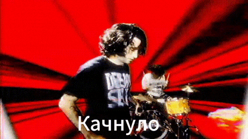 a man in a black shirt is playing drums in front of a red background .