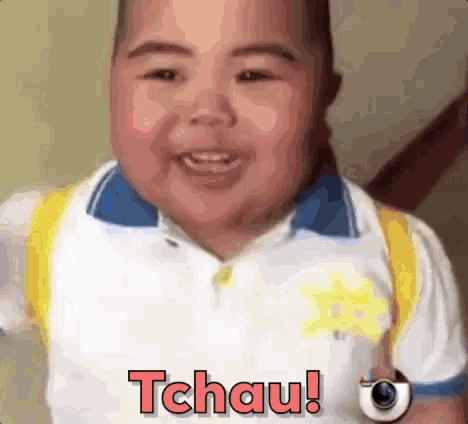 a little boy wearing a white shirt and a yellow backpack is smiling and holding a watch and says tchau !