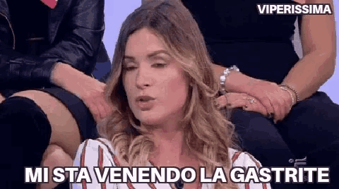 a woman is sitting in front of a group of women and says " mi sta venendo la gastrite "