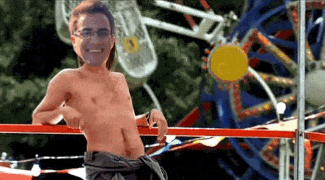 a shirtless man stands in front of a carnival ride
