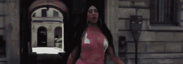 a woman in a pink top and white bra is walking down a street .