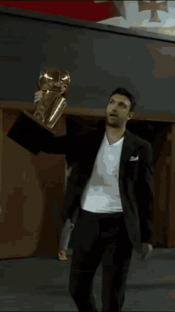 a man in a suit is holding a trophy in his hands